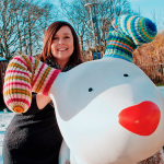 Jane Hogan, poses with giant Snowdog sculpture in a snowy garden