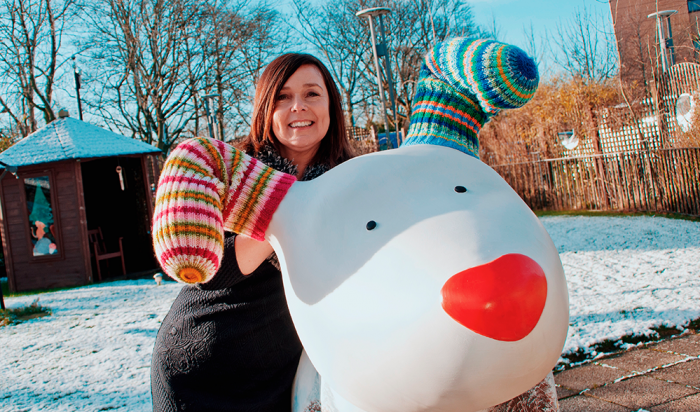 Jane Hogan, poses with giant Snowdog sculpture in a snowy garden